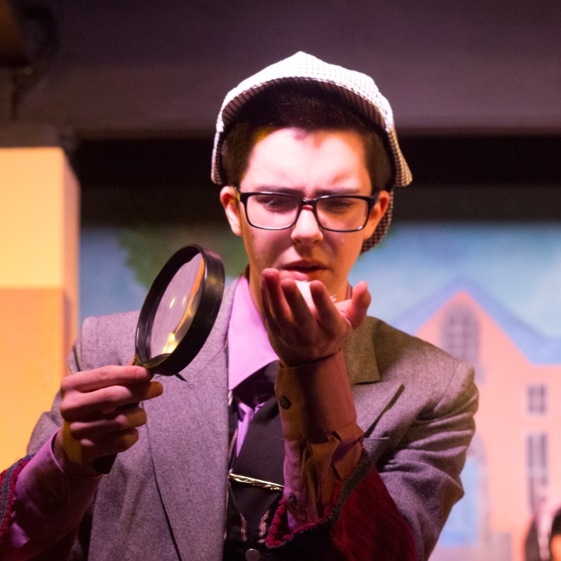 Young male actor dressed as Sherlock Holmes, holding magnifying glass